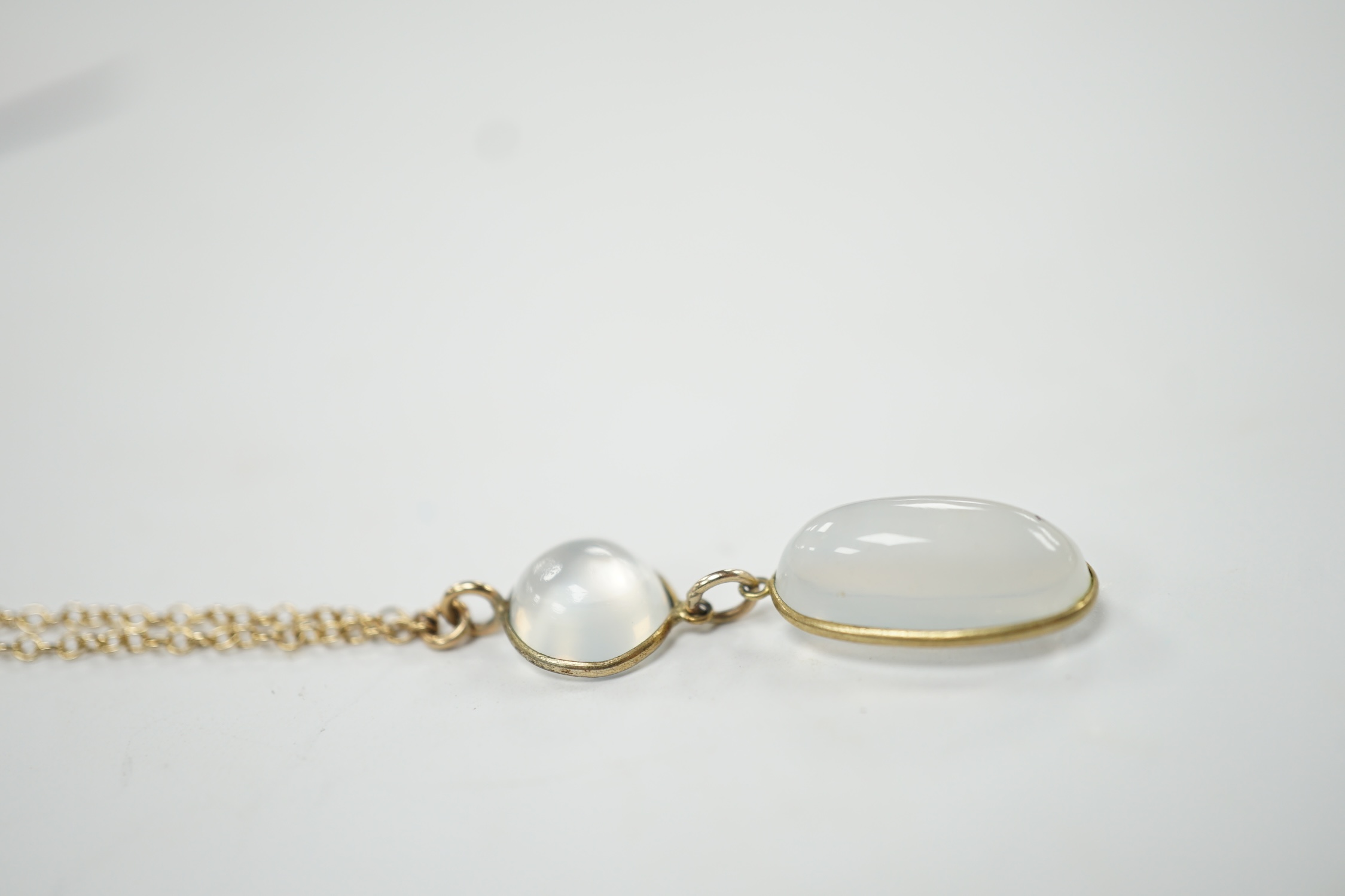 A modern 9ct gold and two stone cabochon moonstone set drop pendant necklace, overall, 47cm, gross weight 3.8 grams. Good condition.